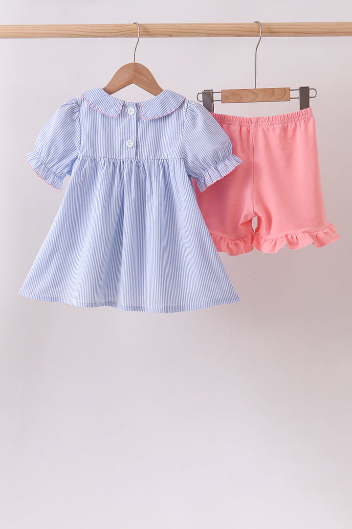 Light blue dress with puffed sleeves and pink shorts on hangers against a light background