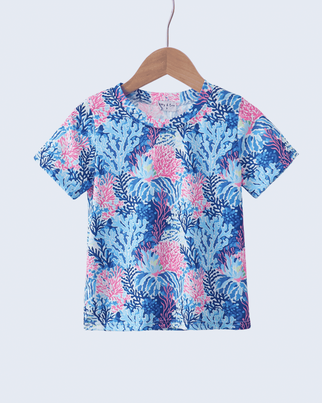 Blue and pink floral patterned top on a hanger against a light blue background
