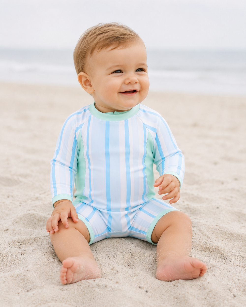 Baby boy on beach wearing Blue stripe one-piece swimsuit