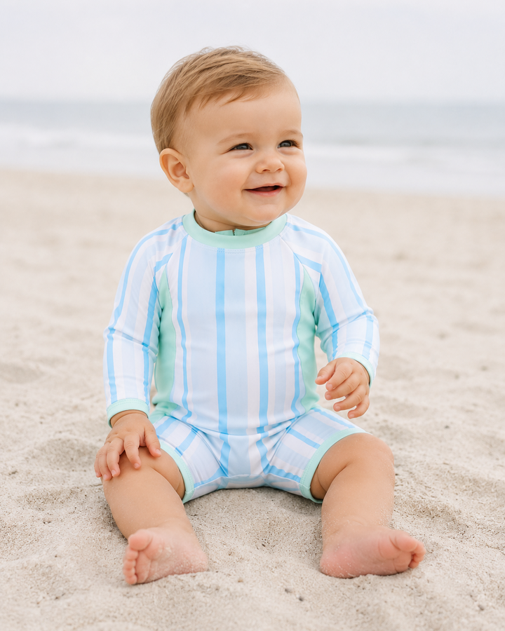 Baby boy on beach wearing Blue stripe one-piece swimsuit