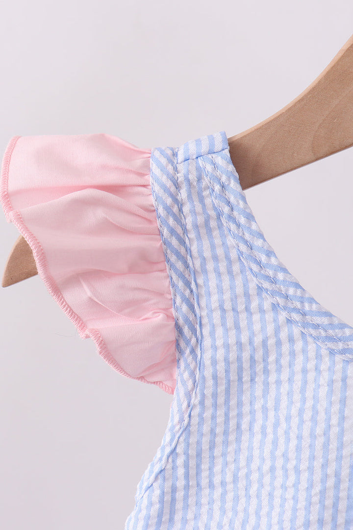 Light blue and white striped swimsuit with pink ruffle on a wooden hanger against a light gray background