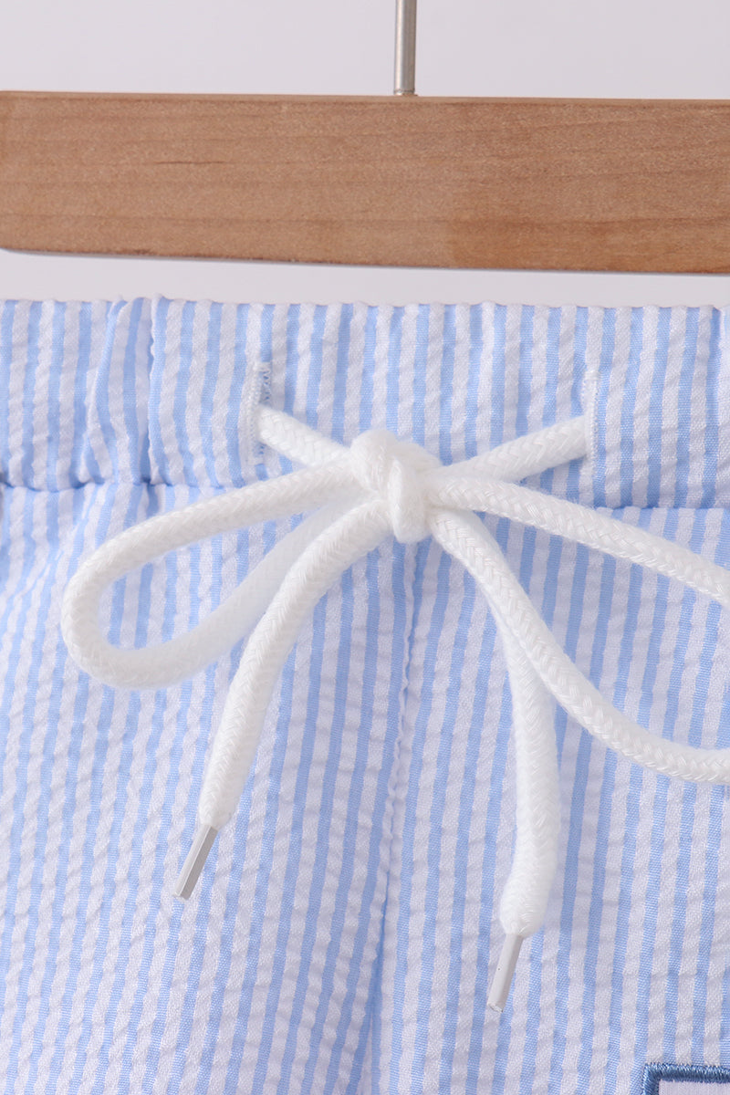 Close-up of a white cord on blue and white striped fabric with a wooden surface in the background.