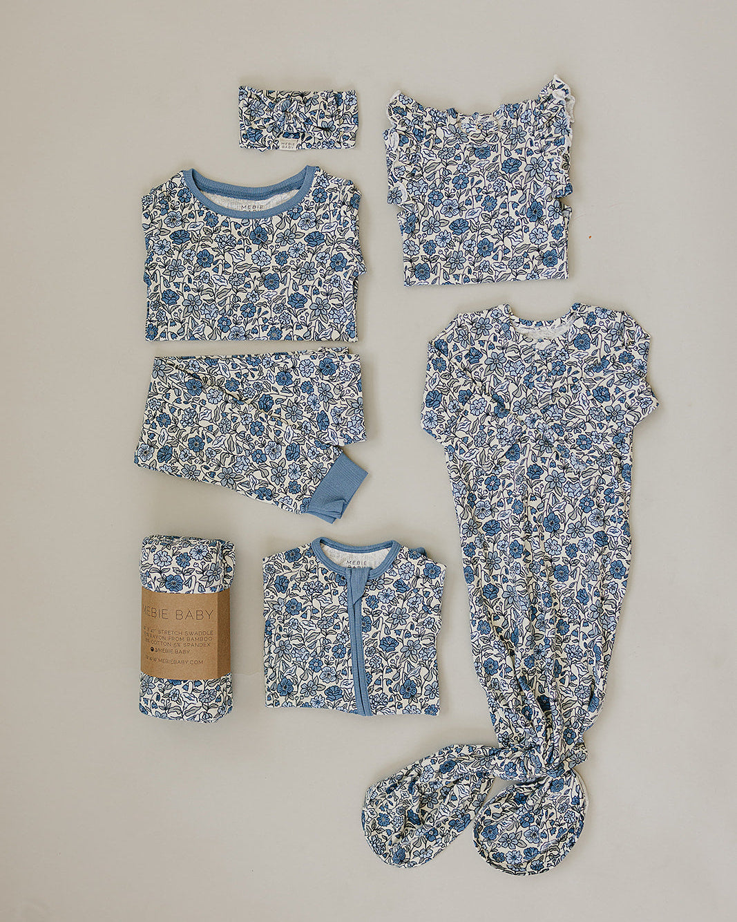 Collection of baby clothing items with blue floral pattern on a beige background