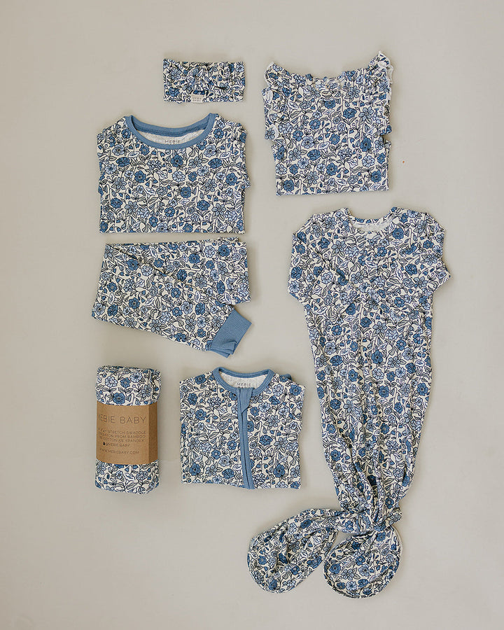 Collection of baby clothing items with blue floral pattern on a beige background