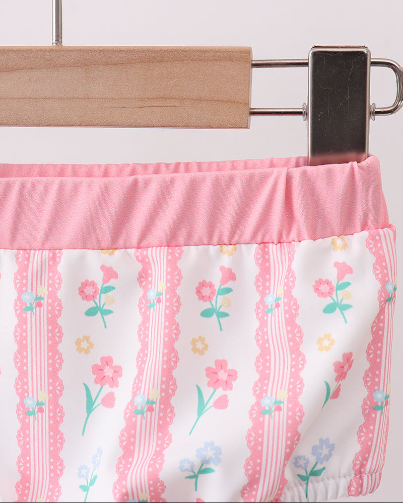 Floral-patterned fabric with pink trim on a hanger against a white background