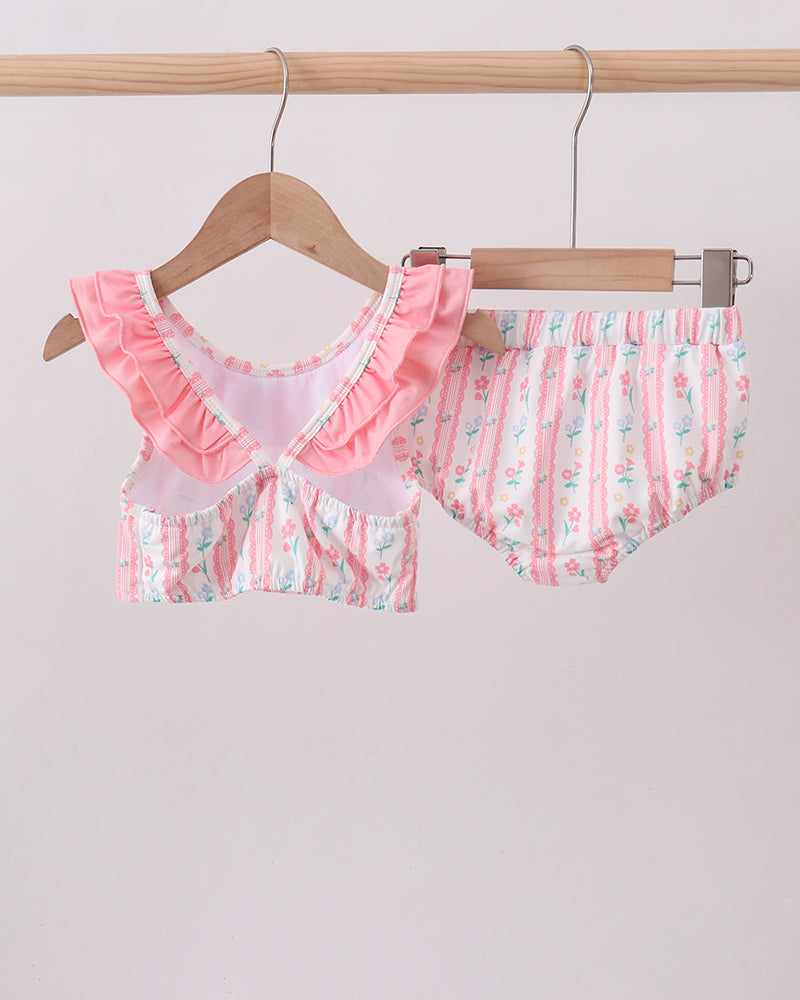 Pink and white swimsuit set on a hanger against a light background