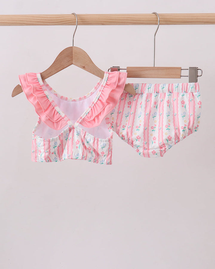 Pink and white swimsuit set on a hanger against a light background