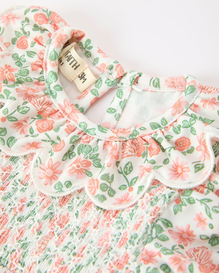 Close-up floral baby romper with ruffled petal collar and gathered neckline