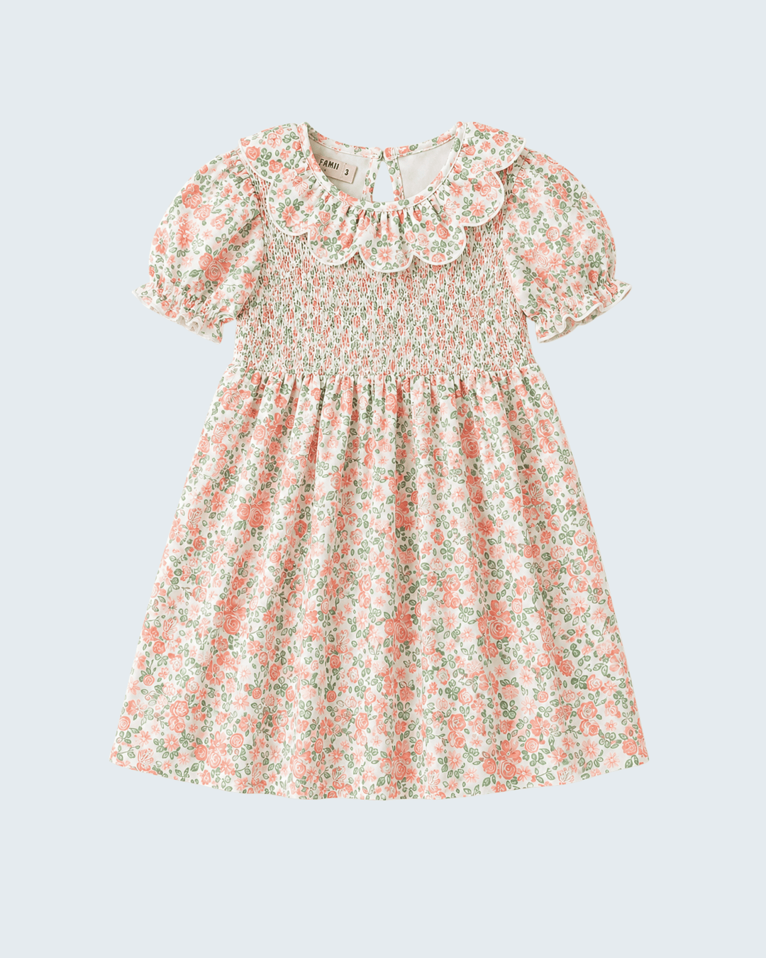 A girl's short-sleeve dress with a smocked bodice, ruffled Peter Pan collar, and a delicate pink and green floral print on a light cream background, shown against a solid light gray background.