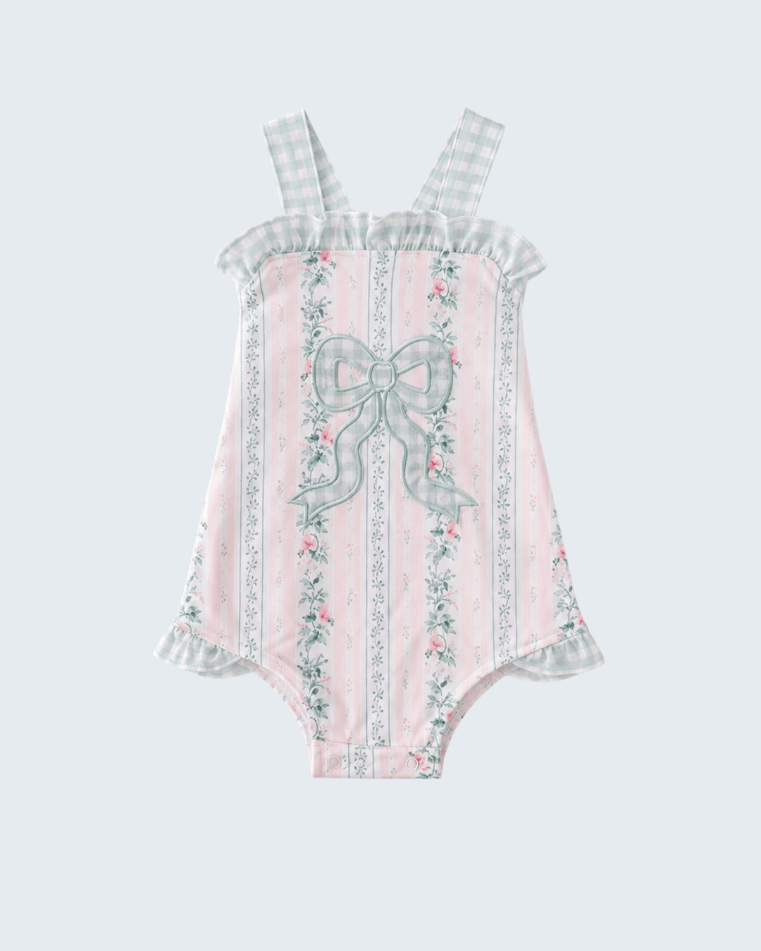 Pink romper with floral and bow details on a light gray background