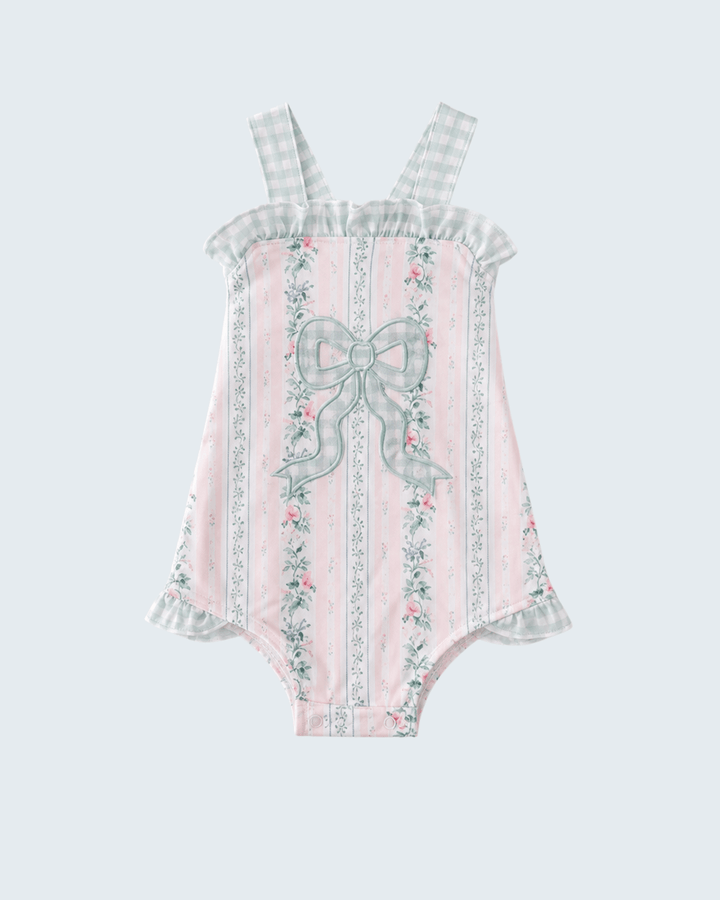 Pink romper with floral and bow details on a light gray background