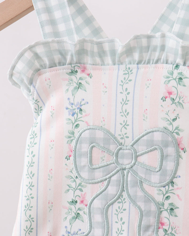 Light blue checkered apron with floral patterns and a large bow on a white background