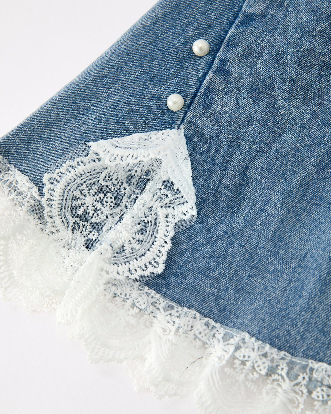 Close-up of girls denim flare jeans with white lace scalloped hem and 2 buttons