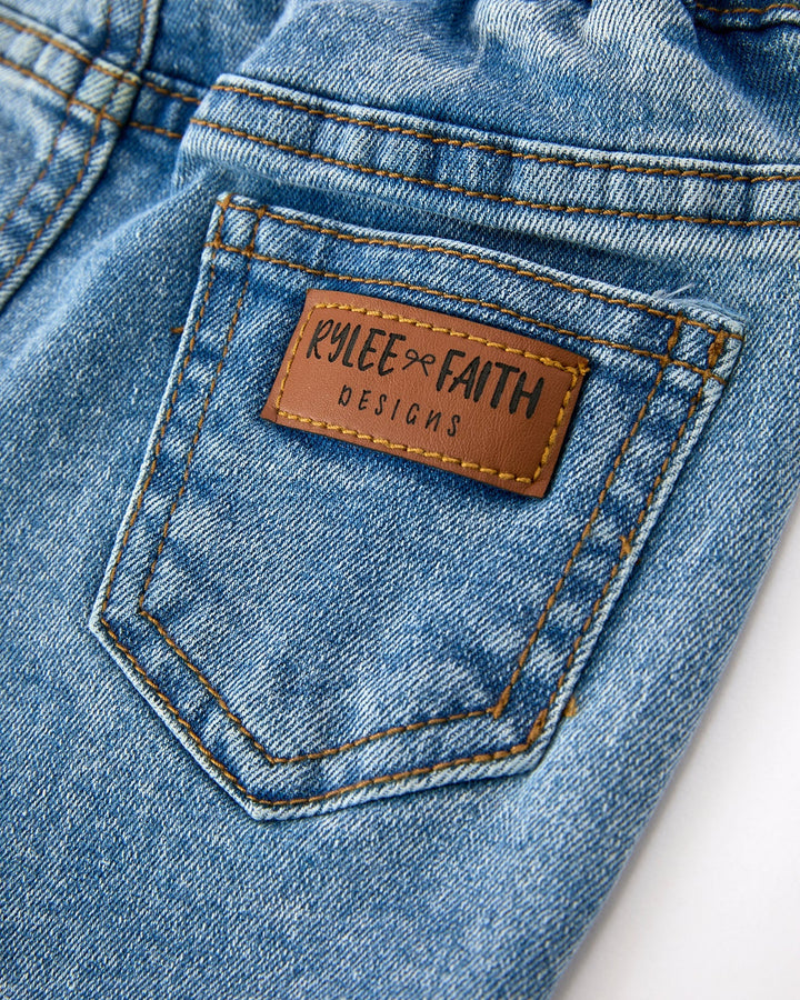 Close-up of girls denim flare jeans pocket with leather-look brand patch