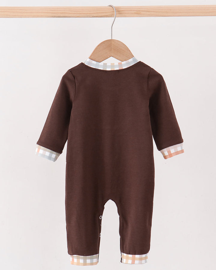 A baby long-sleeve footless romper in dark brown, hanging on a wooden hanger. The romper features contrasting light beige and white gingham trim at the collar, cuffs, and hems.