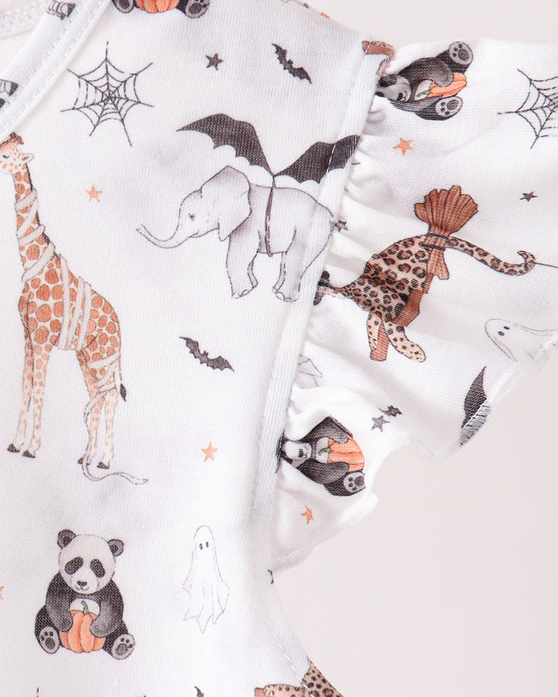 White girls clothing or fabric with a whimsical animal print featuring pandas, giraffes, elephants, leopards, ghosts, bats, and spiderwebs in orange, black, and brown, shown in a close-up studio shot.