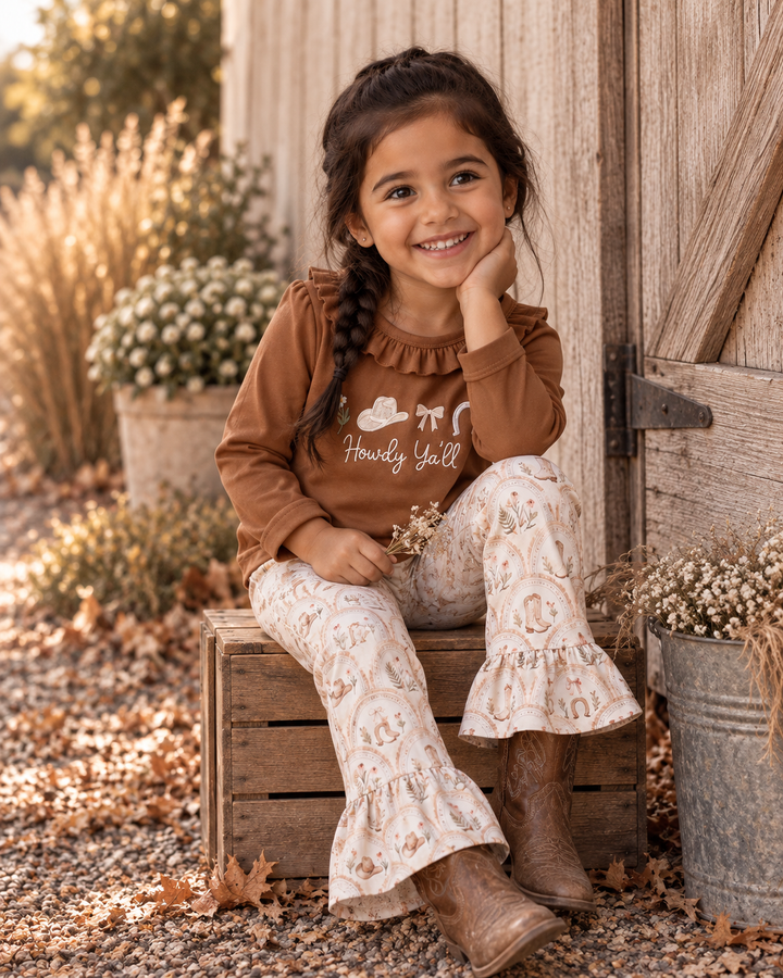 Toddler girl wearing brown embroidered ruffle top and cream patterned bell pants