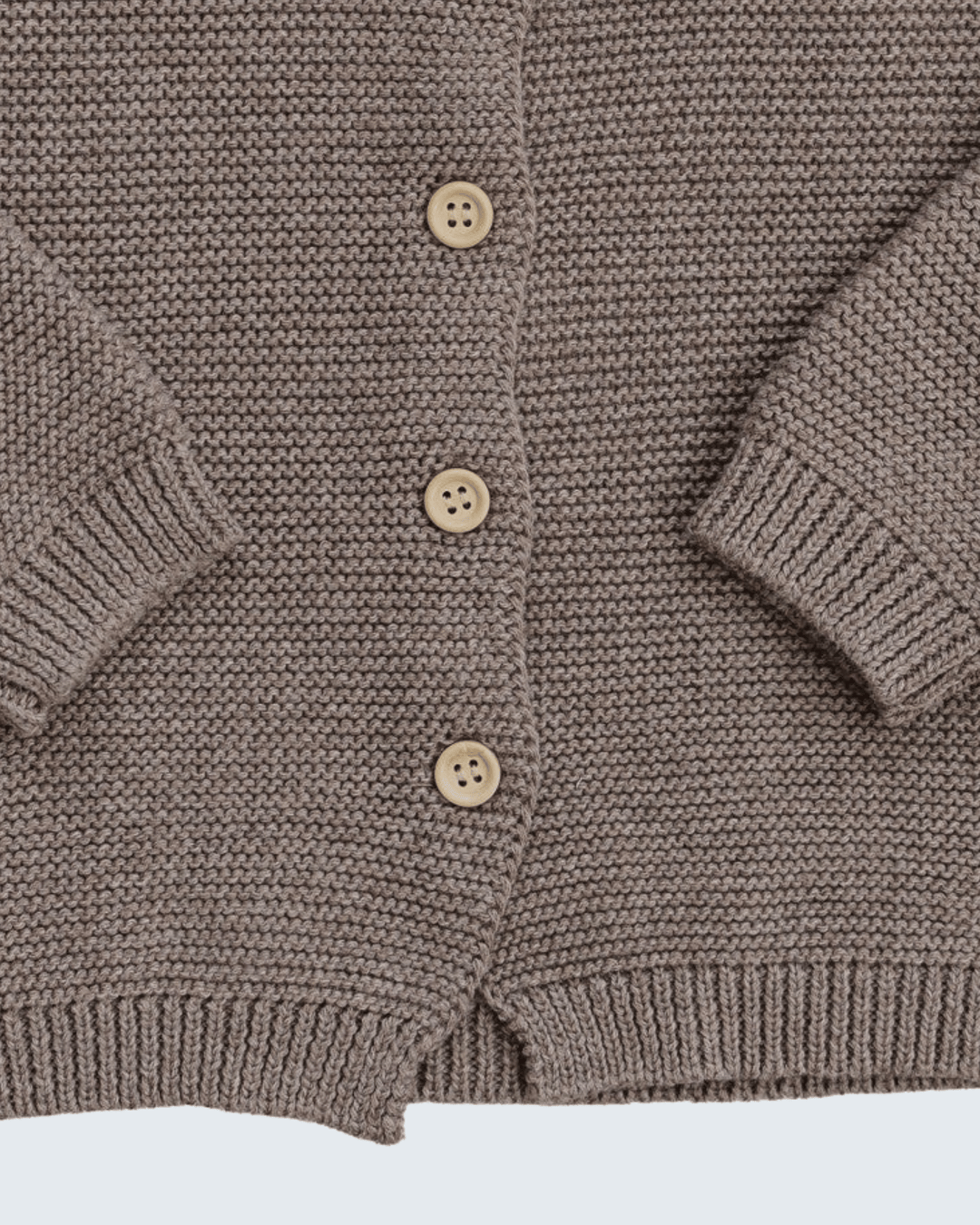 Close-up of a brown ribbed knit cardigan with four light beige buttons, showing the texture and sleeve cuffs.