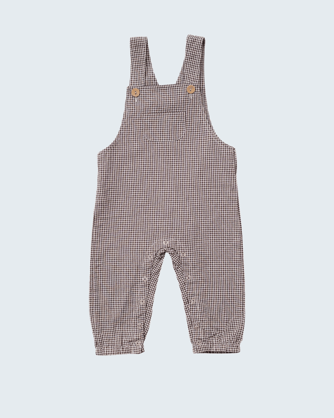 A baby romper in a brown and white gingham check pattern, featuring adjustable shoulder straps with two small wooden buttons and a cuffed leg.