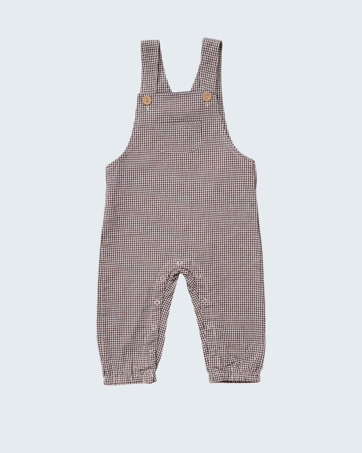 A baby romper in a brown and white gingham check pattern, featuring adjustable shoulder straps with two small wooden buttons and a cuffed leg.