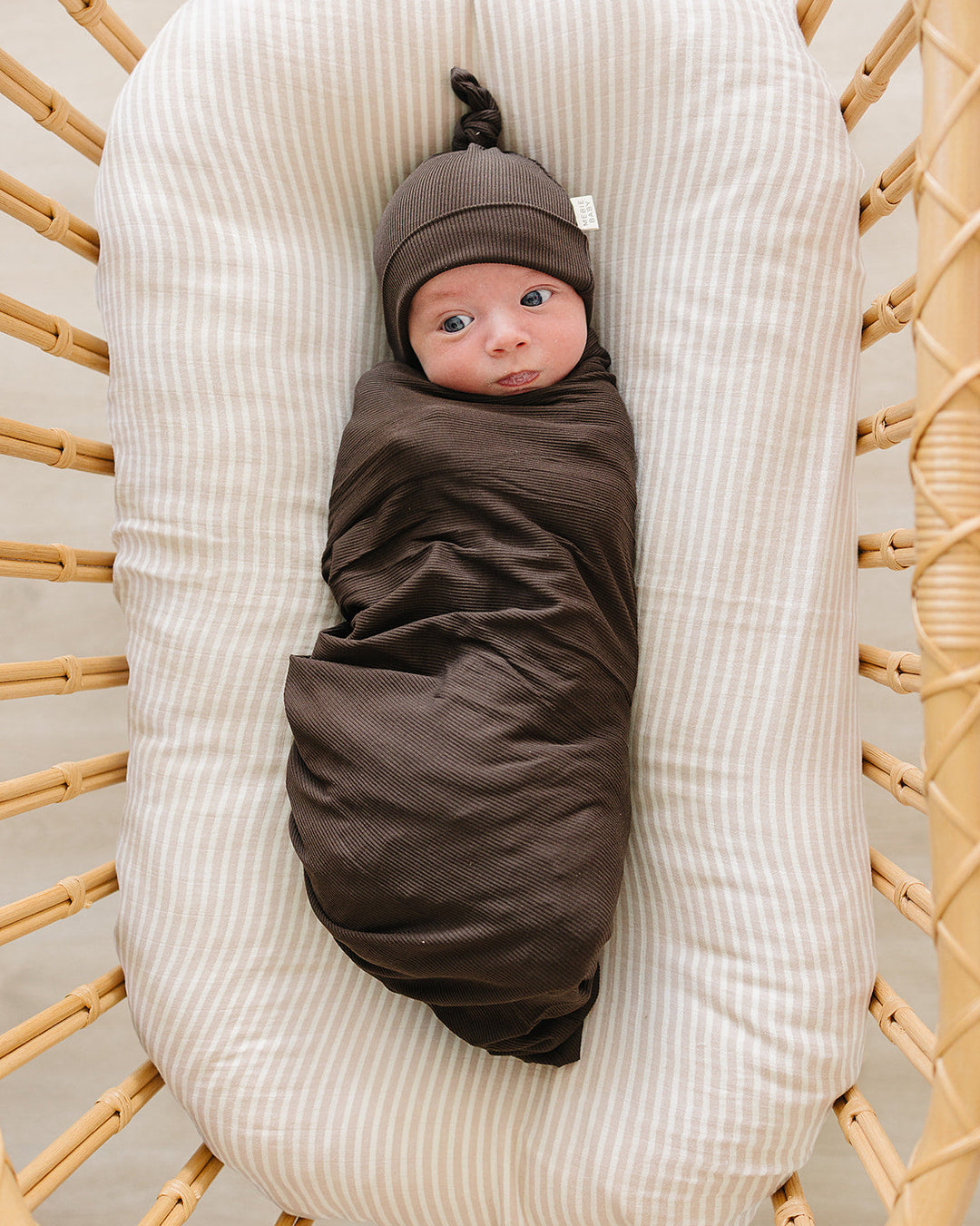 Dark brown ribbed newborn knot hat on baby’s head, with gathered top knot.