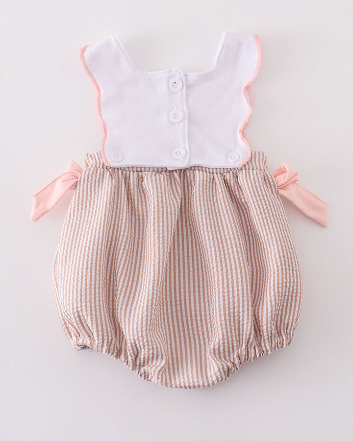 Baby romper with white top and brown checkered bottom on a light gray background
