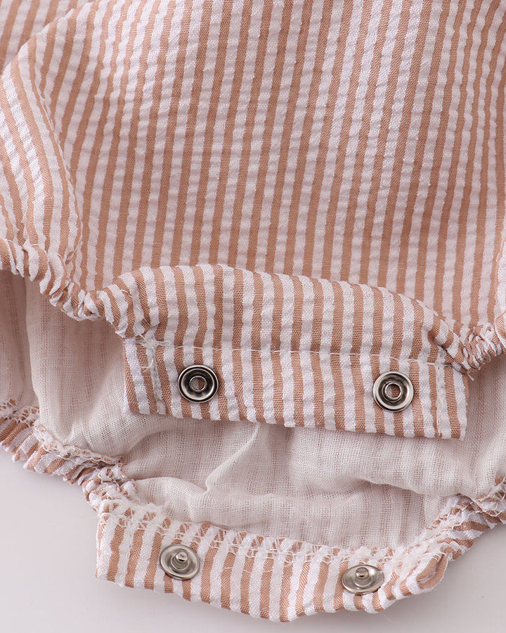 Close-up of a baby romper with pink and white stripes on a light background
