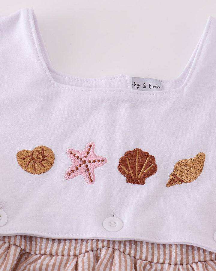 White baby romper with shell and starfish appliqués on a white background