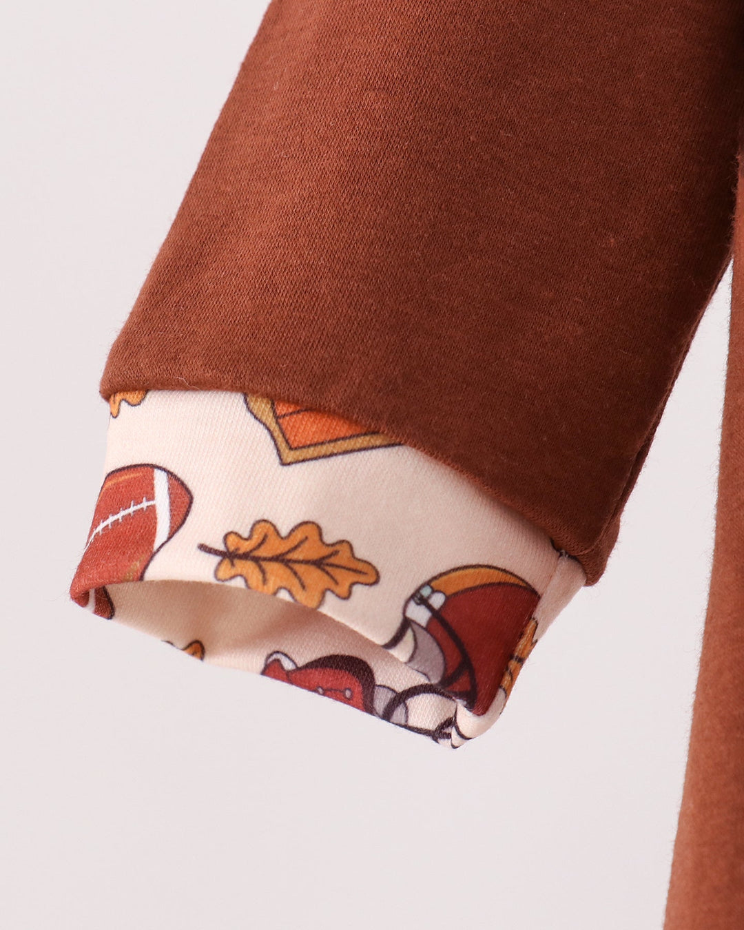 Brown romper sleeve cuff with playful football print hem