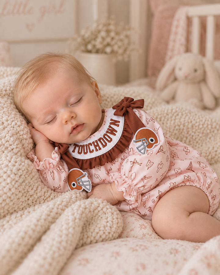 Pink patterned bubble romper with brown bow shoulder accents and touchdown embroidery