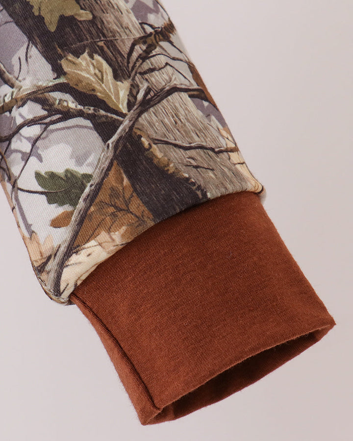Tree-camouflage pullover sleeve with brown knit cuff and woodland print