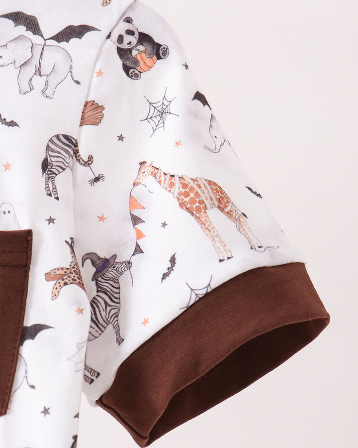 A close-up of a short-sleeve shirt featuring a white base with a colorful animal print including giraffes, zebras, pandas, and bats, finished with a solid brown ribbed cuff.