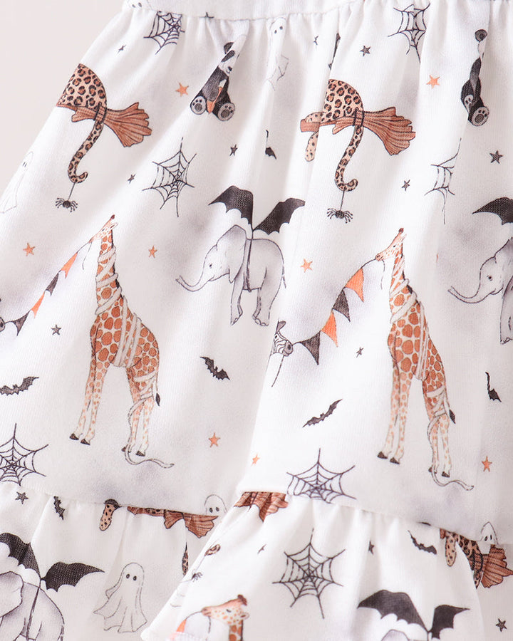 White ruffled baby skirt with a Halloween print featuring orange-brown giraffes, gray elephants, black bats, ghosts, spiderwebs, and orange stars.
