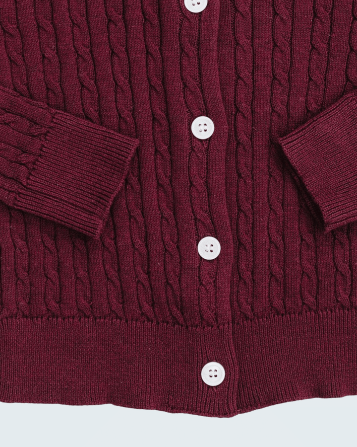 Close-up of a burgundy cable-knit cardigan sweater showing the button closure with white buttons and ribbed cuffs.