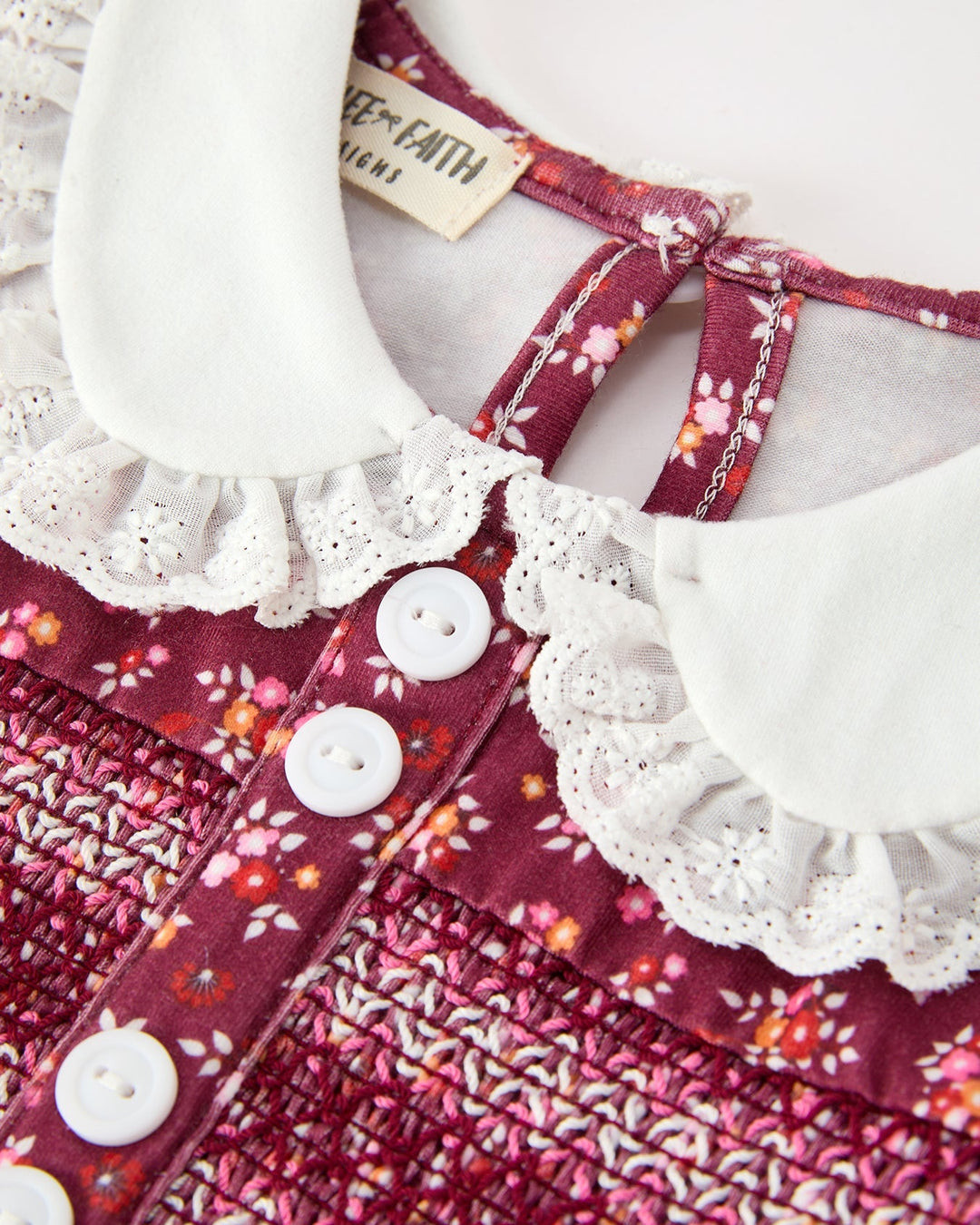 Close-up of burgundy floral bubble romper with white lace-trim Peter Pan collar and buttons