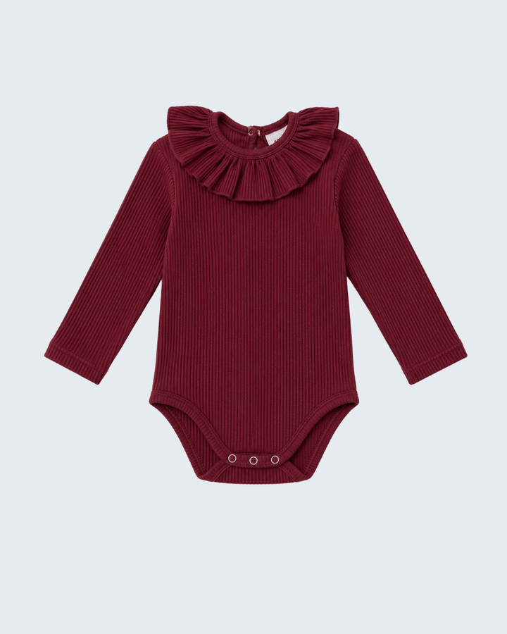 A long-sleeve ribbed baby bodysuit in deep burgundy, featuring a large ruffled collar and snap closures at the crotch, shown against a light gray background.
