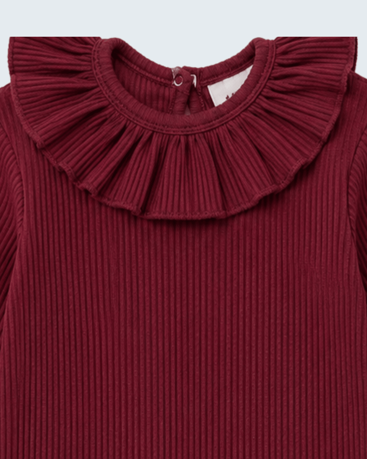 Close-up of a ribbed knit top in deep burgundy red, featuring a wide pleated ruffle collar and long sleeves.