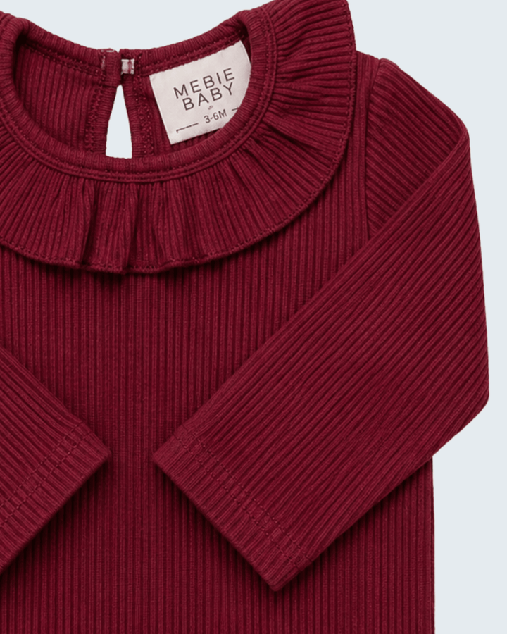 Burgundy ribbed long-sleeve top with ruffle neckline and snap placket, close-up