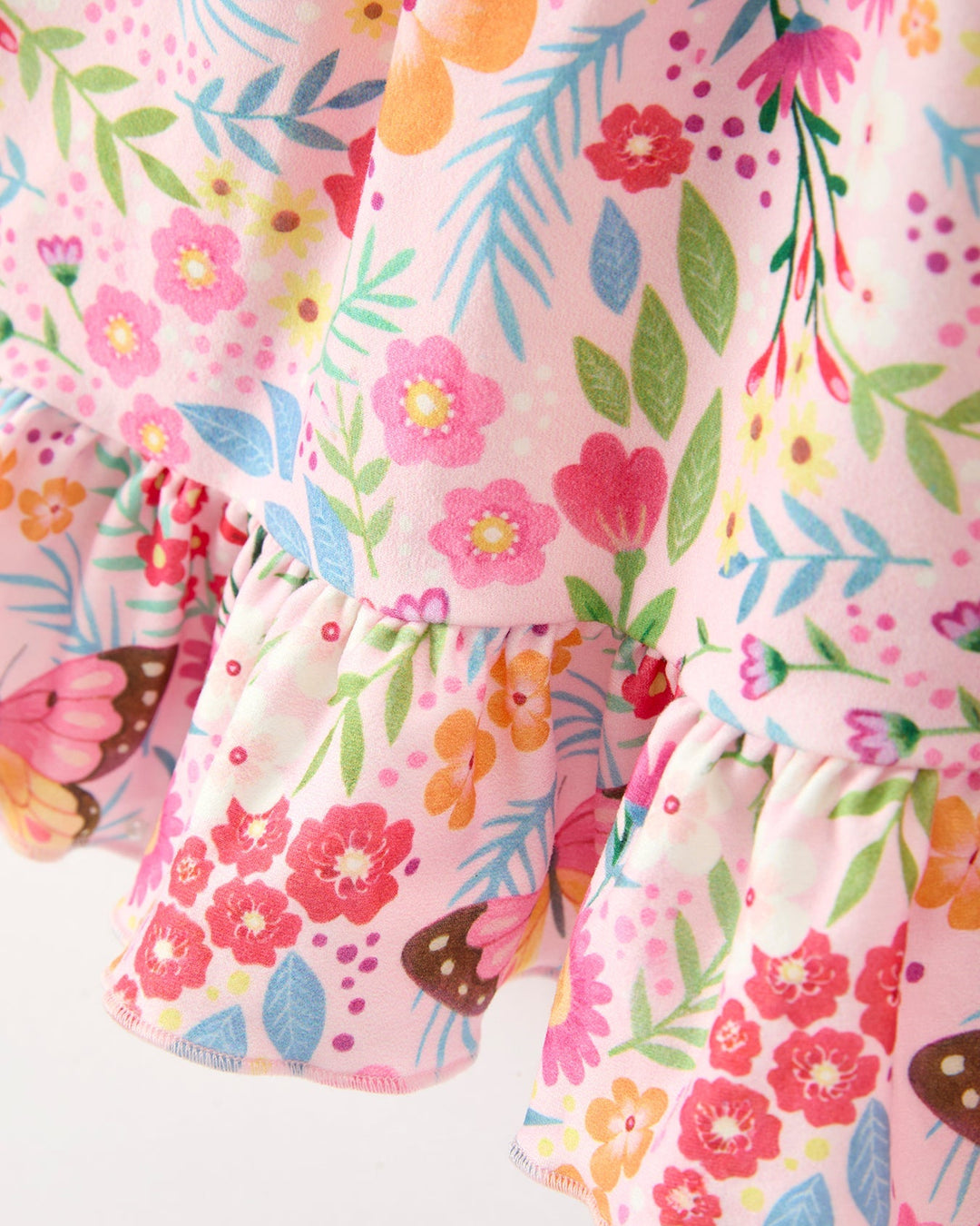 Close-up of a floral patterned fabric with pink, orange, and green colors on a white background.