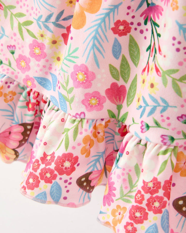 Close-up of a floral patterned fabric with pink, orange, and green colors on a white background.