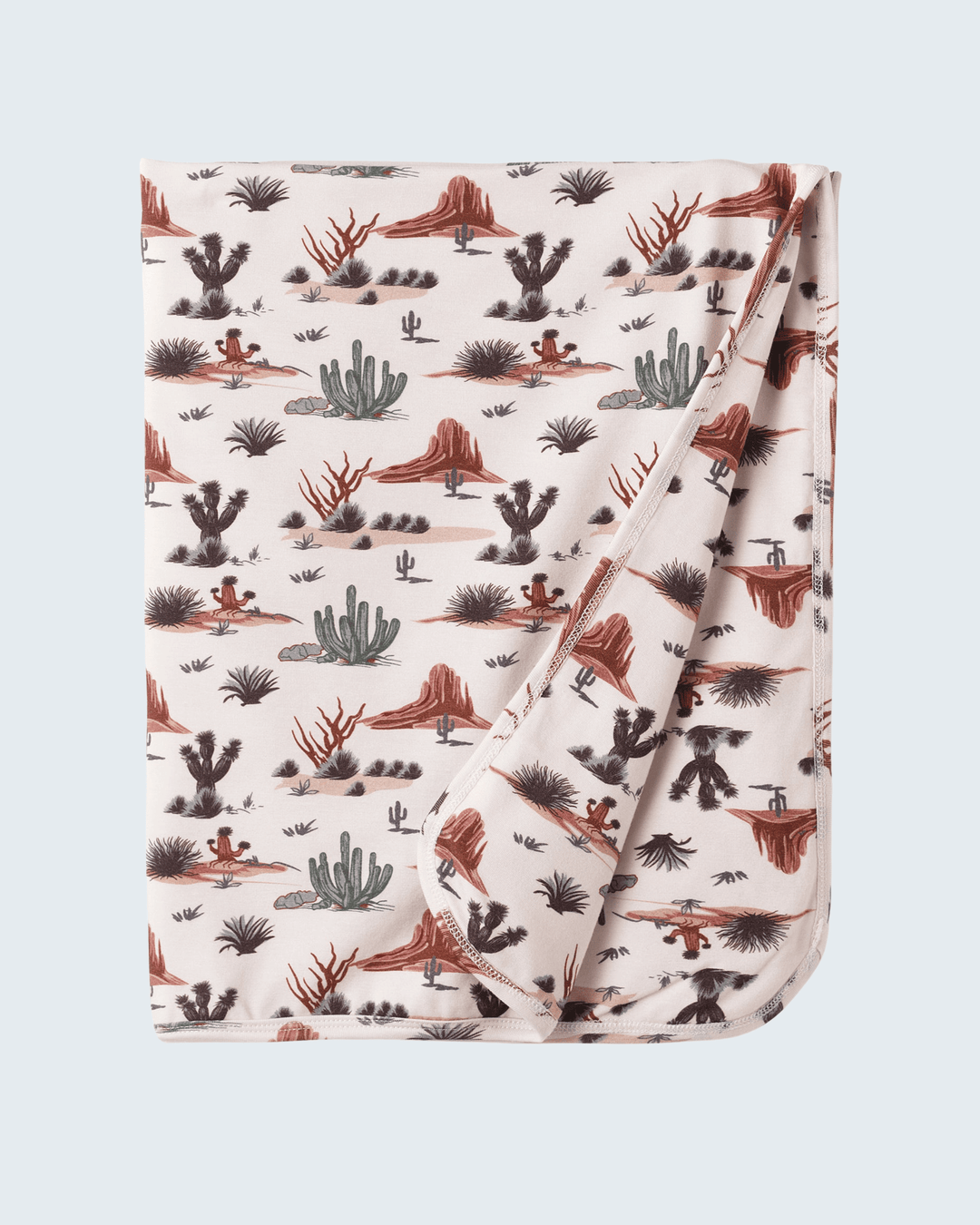 Folded baby blanket with desert landscape pattern on a light gray background