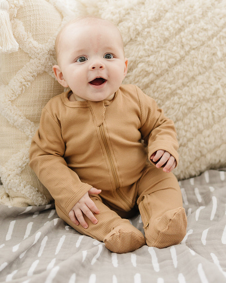 Tan ribbed cotton zipper romper on baby, long sleeves and footed legs