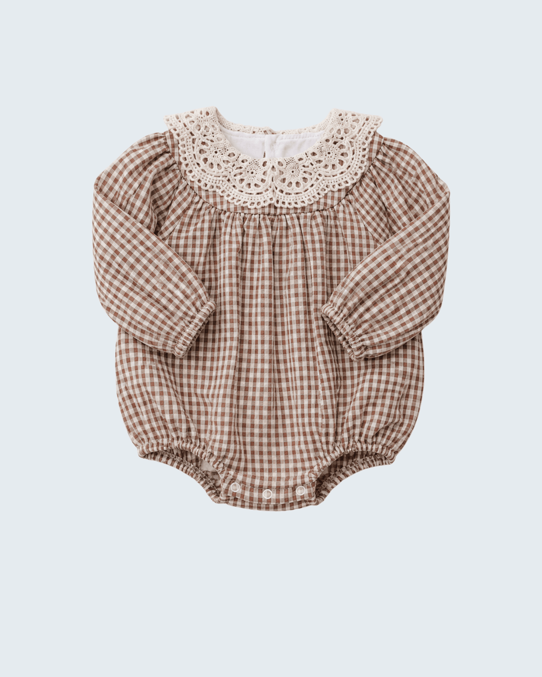 A baby long-sleeve romper in a brown and beige gingham pattern, featuring a cream-colored crochet lace collar, laid flat against a light gray background.