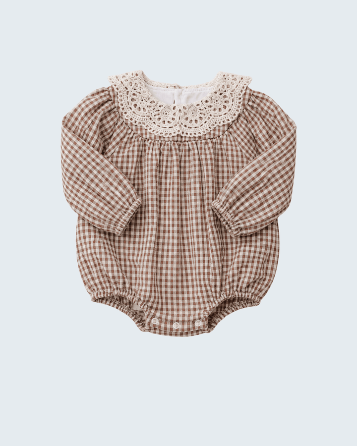 A baby long-sleeve romper in a brown and beige gingham pattern, featuring a cream-colored crochet lace collar, laid flat against a light gray background.