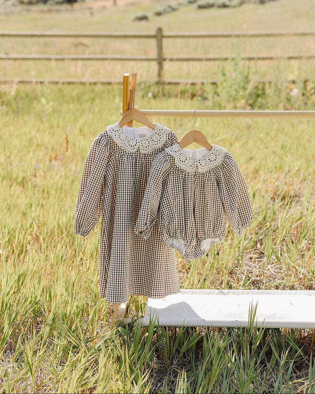 Camel gingham bubble romper with lace collar on a wooden hanger