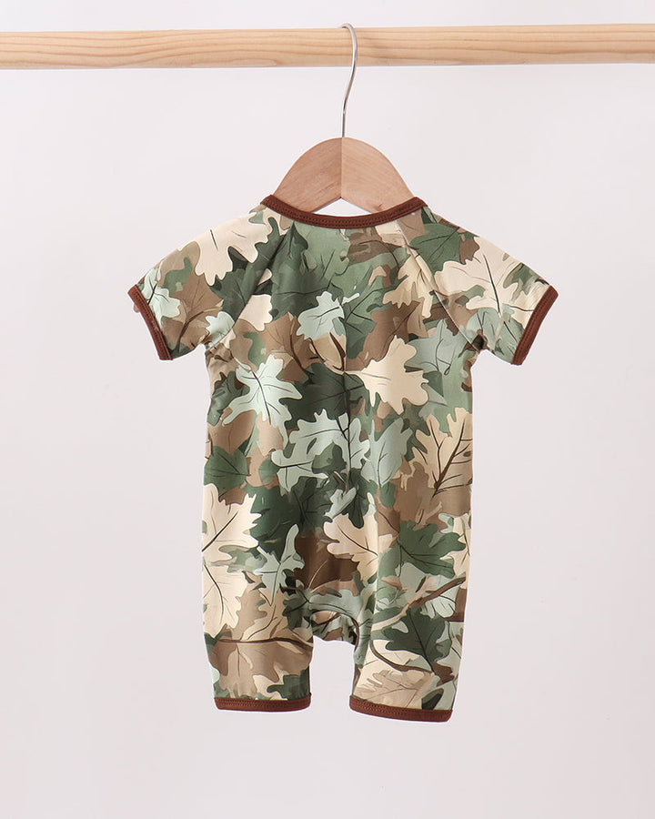 Camouflage-patterned baby romper on a wooden hanger against a white background