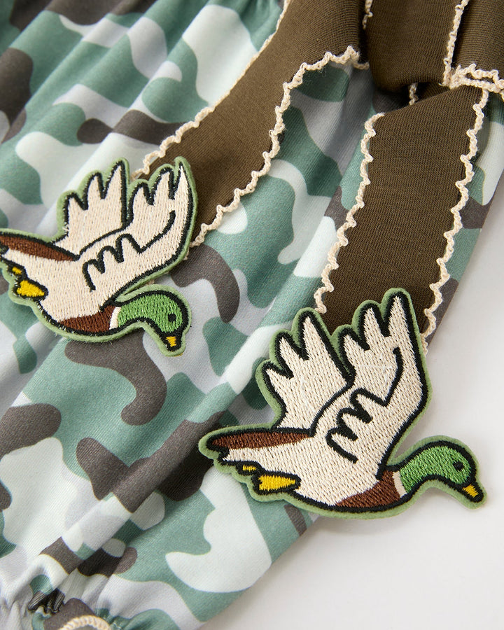 Camouflage romper with embroidered dinosaur patches and brown scalloped edges