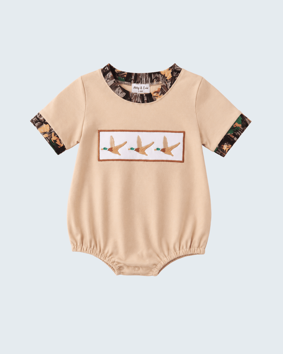 Beige baby romper with camouflage sleeves and duck design on a light blue background