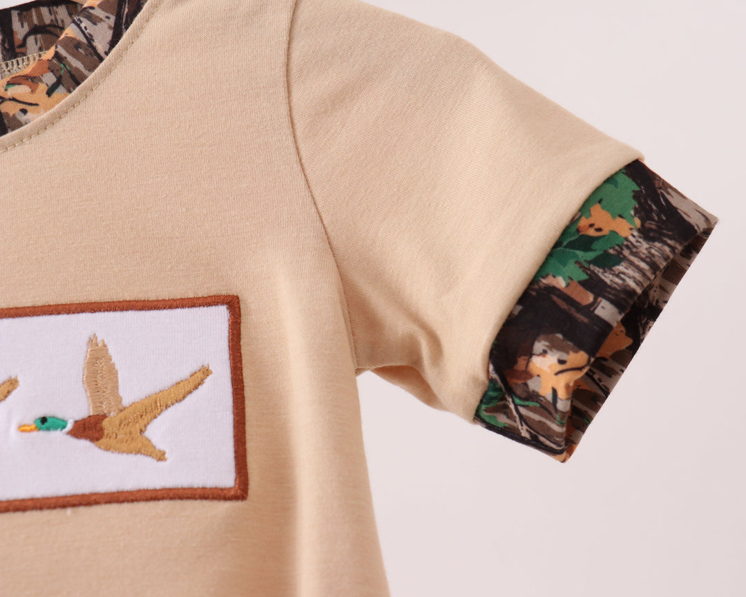 Beige shirt with duck hunting-themed patch and sleeve design on a light gray background