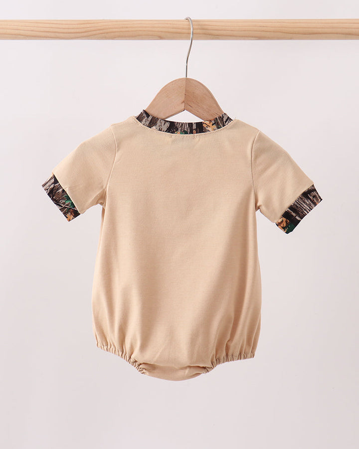 Beige baby romper with patterned sleeves on a wooden hanger against a white background